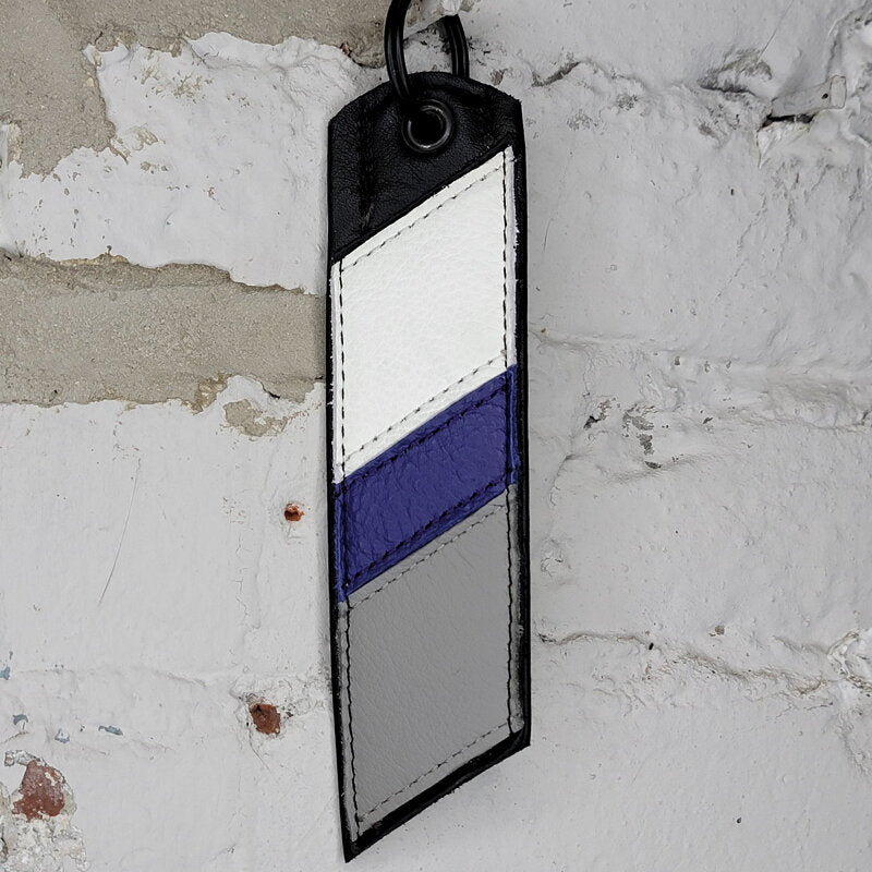 Demisexual pride flag key ring against a wall 