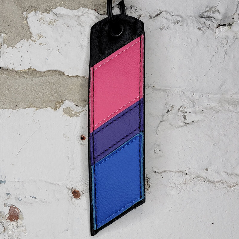 Bisexual pride flag key ring against a wall