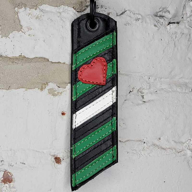 Boy Pride pride flag key ring against a wall