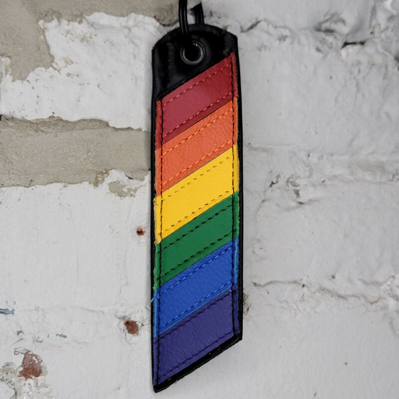 Rainbow pride flag key ring against a wall