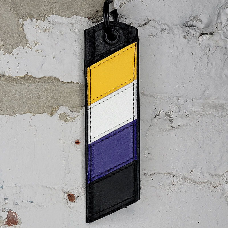 Nonbinary pride flag key ring against a wall