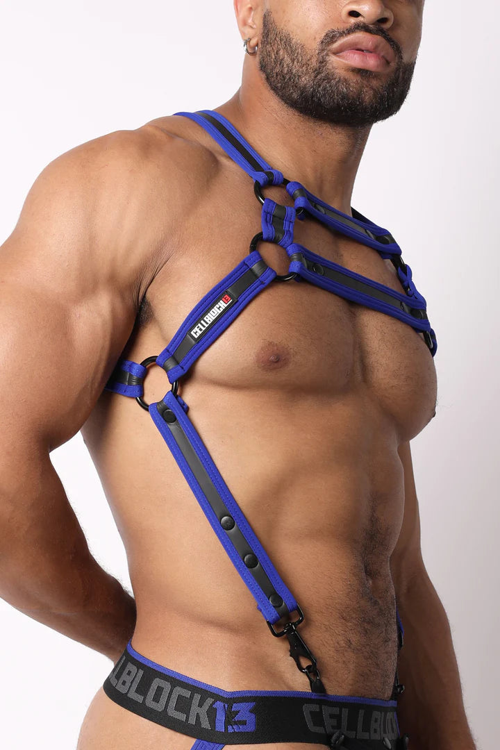 A masculine looking model showing the right side of the blue High Bar Neoprene Suspender Harness.