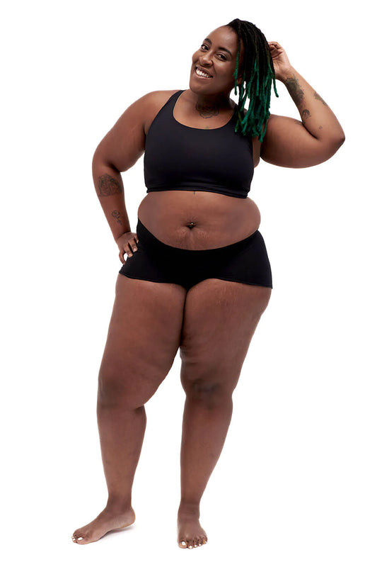 A model in black spandex shorts wears the black Gentle Binding Compression Top.