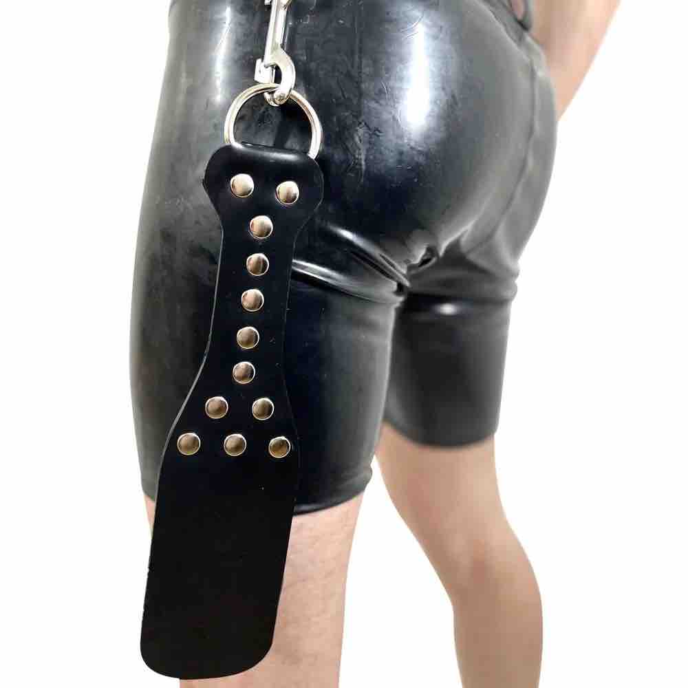 The Rubber Paddle hanging from the waist of a model wearing rubber shorts.
