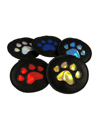 Five leather harness pup paw medallions of various colors.