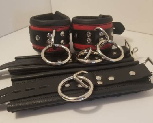 Pair of red Rolled Fleece Ankle Restraint Cuffs displayed buckled next to a pair of black Rolled Fleece wrist restraints that are laying flat.