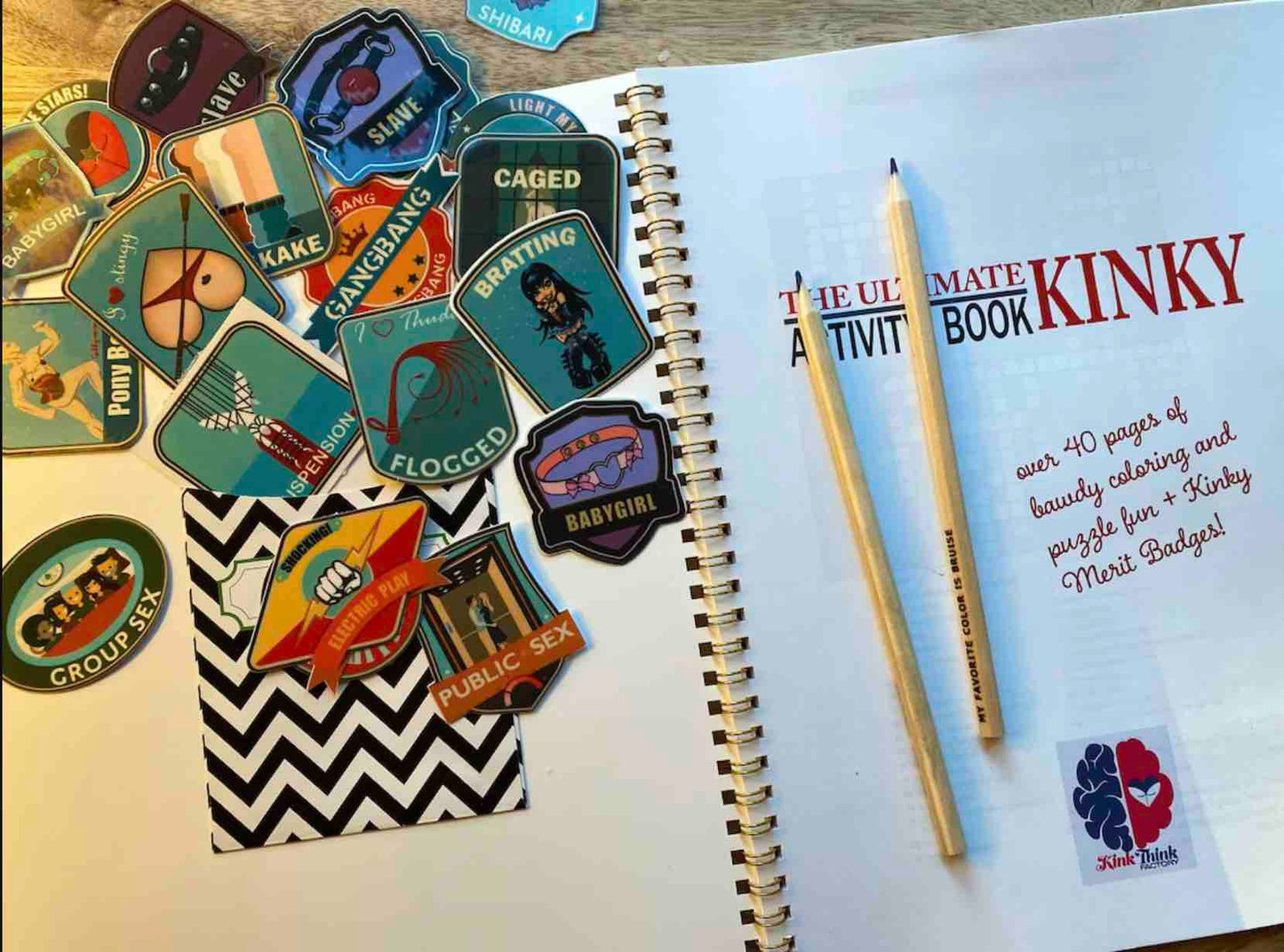 A page from the Ultimate Kinky Activity Book: On the left is a pile of kinky merit badge stickers and the right page is the opening cover for the book.