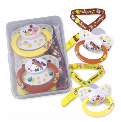 The packaging of the Rearz Barnyard Character Pacifiers with Clips with two pacifiers displayed next to it.
