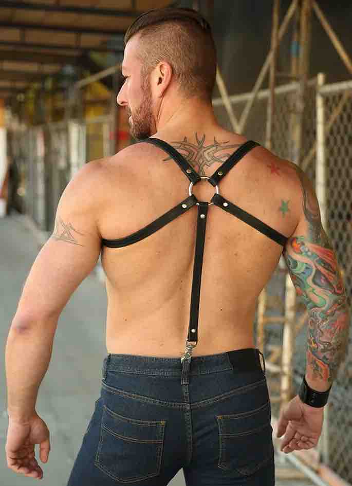 Shirtless model wearing jeans and showing the back of the Leather Double Strap Suspender Harness with one set of straps under the armpits.