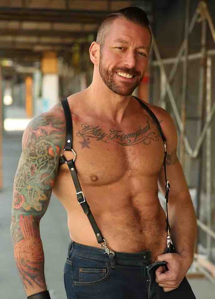 Shirtless model wearing jeans and showing the front of the Leather Double Strap Suspender Harness with one set of straps under the armpits.