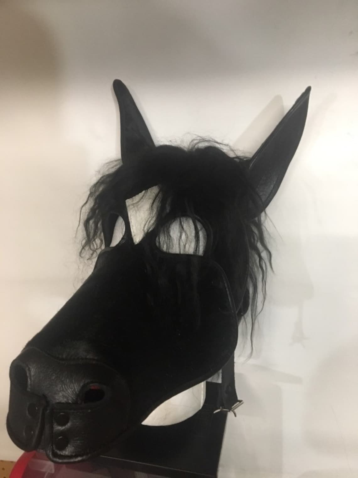 Black leather horse mask on a mannequin, front view.