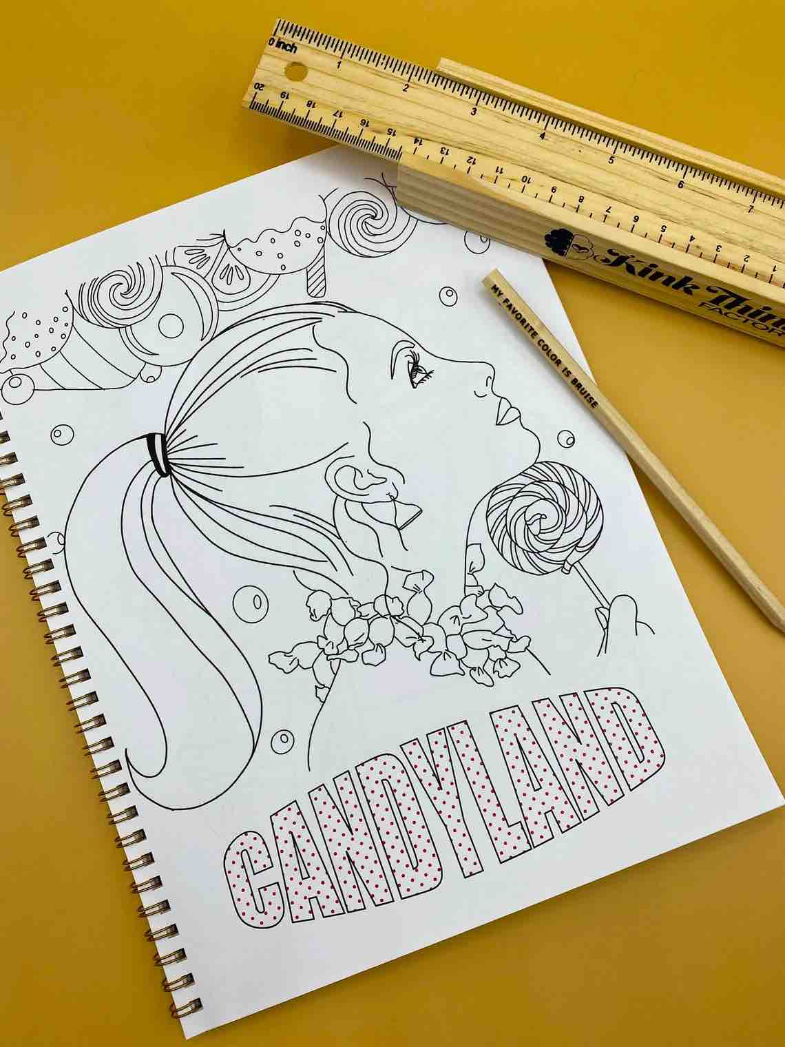 A page from Naughty and Nice: A Coloring Book for Babygirls. A girl with her hair in a ponytail holding a swirled lollipop under her chin. There are sweet treats above her head and below is text that reads CANDYLAND.