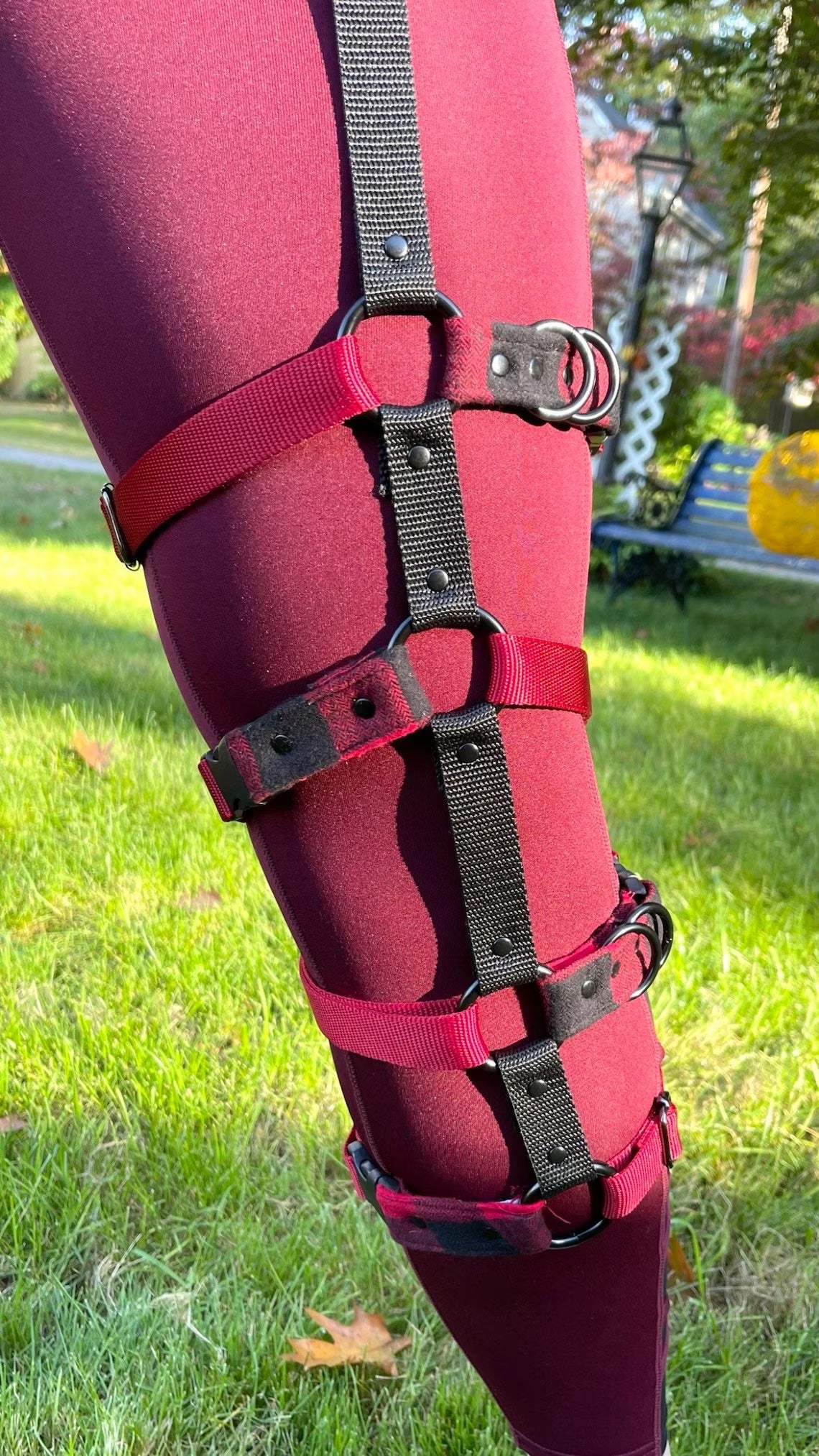 A model bound in the Leg harness. There is a long vertical strap that goes from the waist down to the calves and four horizontal straps that give it a cage look.