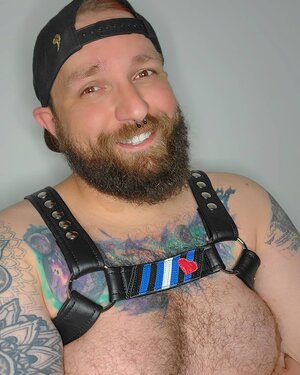 A model showing the front of a harness with the Leather Pride Flag Center Strap. 