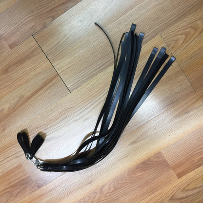 black rubber finger loop flogger on wood floor