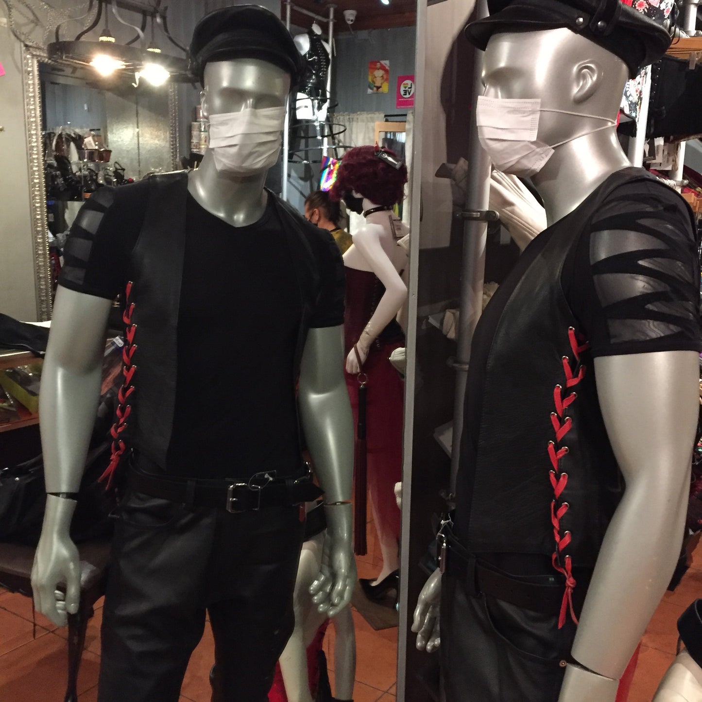 Side views of two mannequins wearing the black cowhide bar vest with red laces.