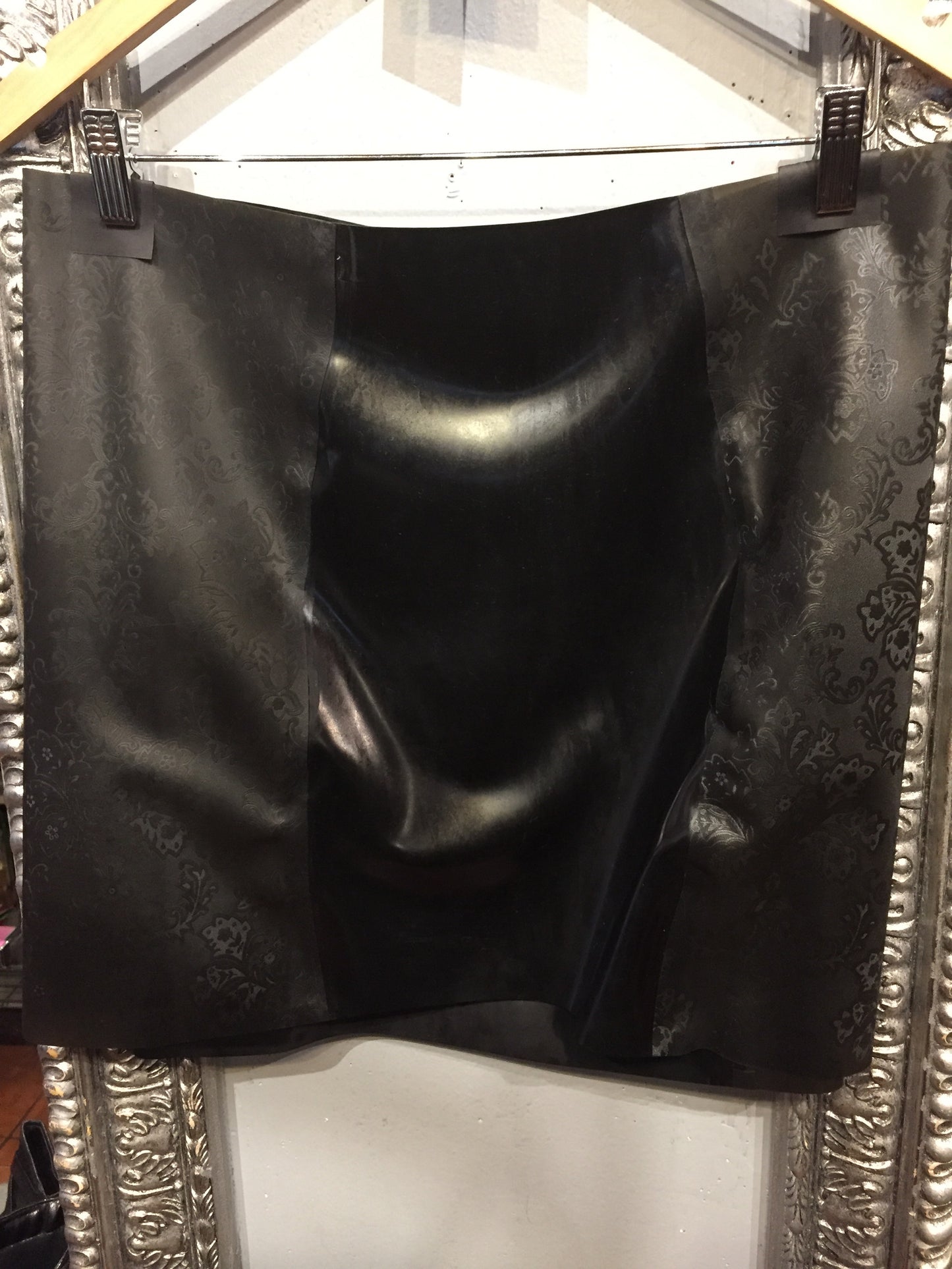 The back of the full black Latex Girdle Mini Skirt on a hanger.