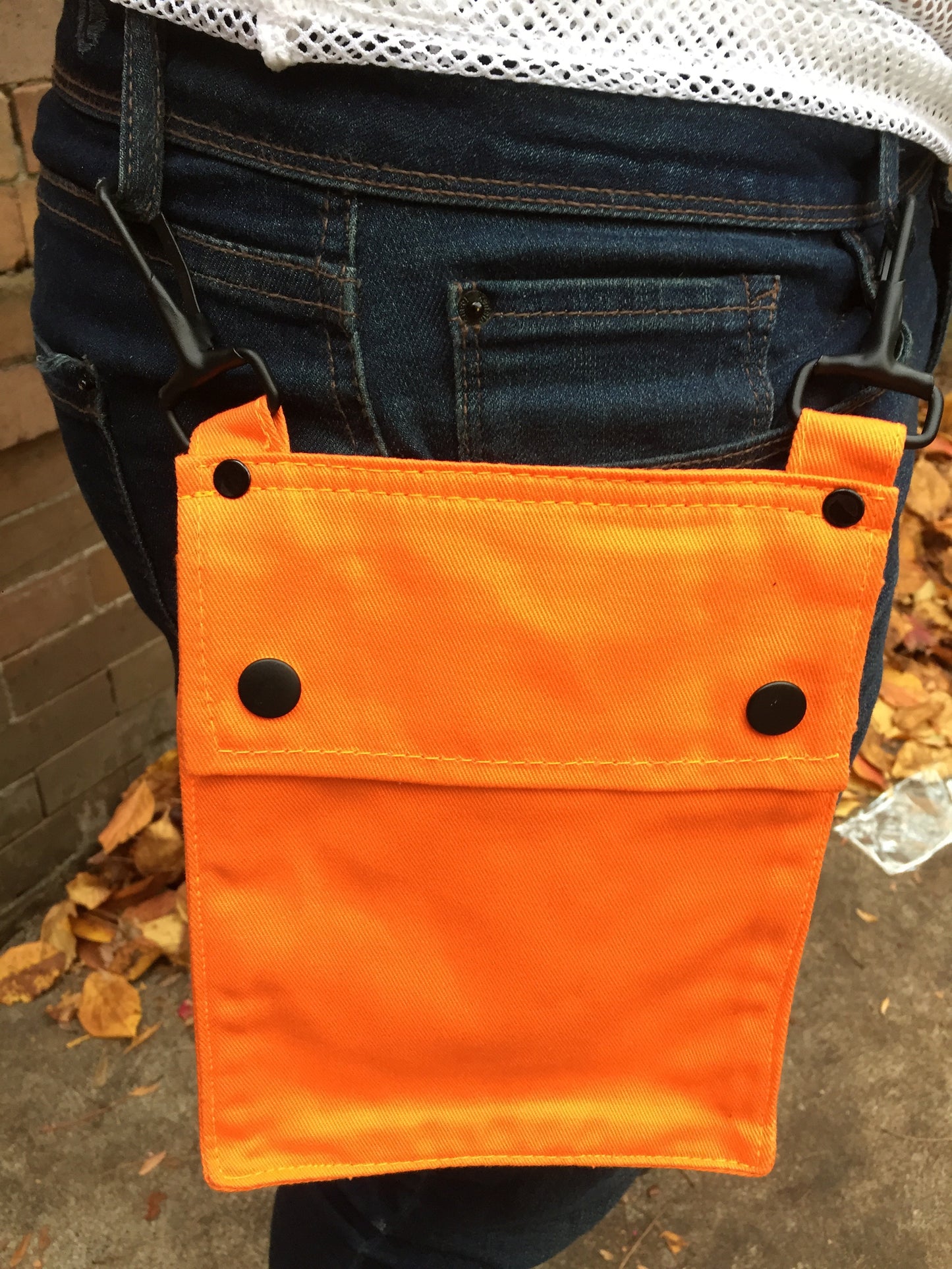 A model wearing the orange Detachable Pocket for Heritage Kilt hooked to their jeans belt loops.