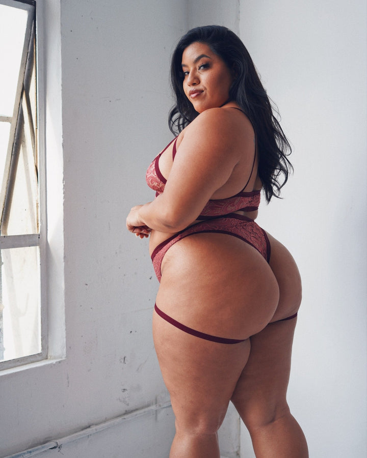 A model displaying the back of the plus size raspberry fields Lace Livi Thong.