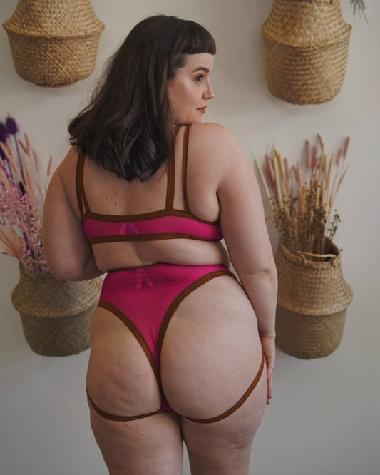 A model showing the back of the plus size dragonfruit Mesh Livi Thong along with matching bralette.