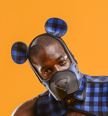 Masculine looking model wearing blue plaid Neoprene Snap-On K-Br Ears attached to the Neoprene K-Hood Base, along with matching muzzle and harness. 