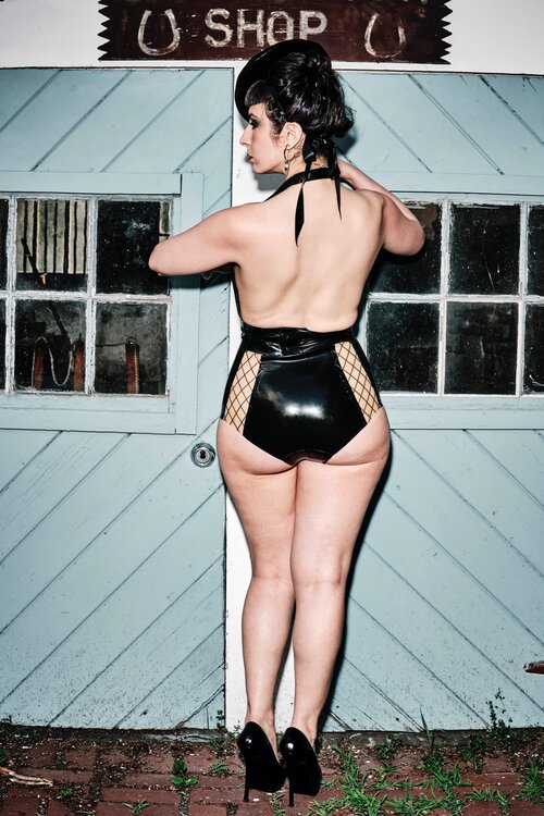 Model wearing a latex halter top with the black and fishnet Specialty Classic Latex Panel Panty, rear view.