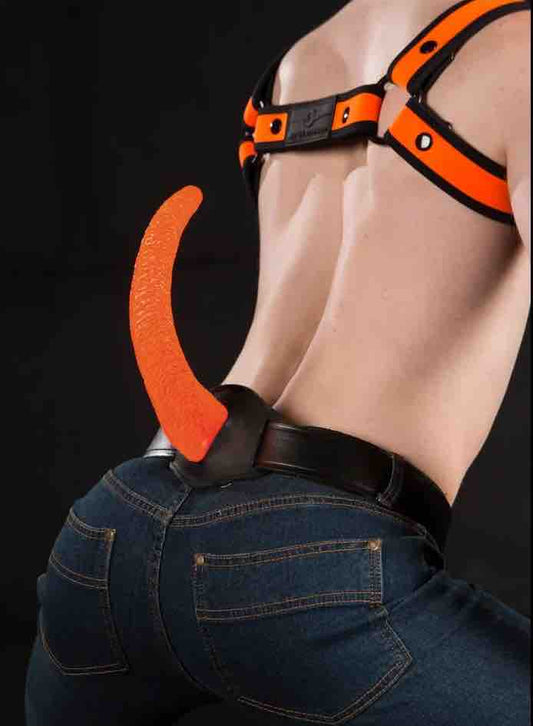 A model wearing an orange chest harness, jeans and the orange Woofy Show Tail with Leather Base on the Show Tail Waist Strap.