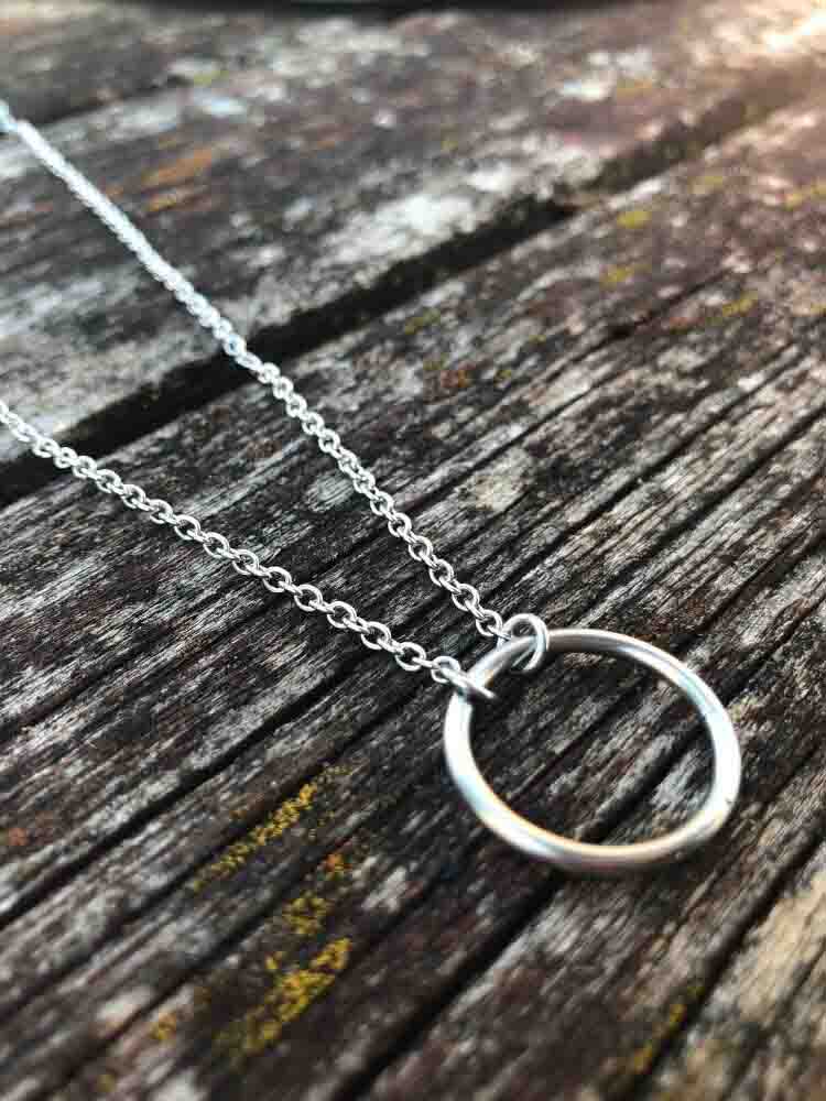 The Eternity Ring Day Collar lying on a wood surface.