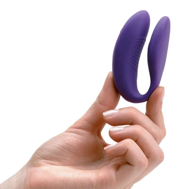 A hand holding the purple We-Vibe Sync.
